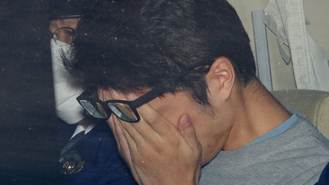 Takahiro Shiraishi covers his face inside a police car in Tokyo 